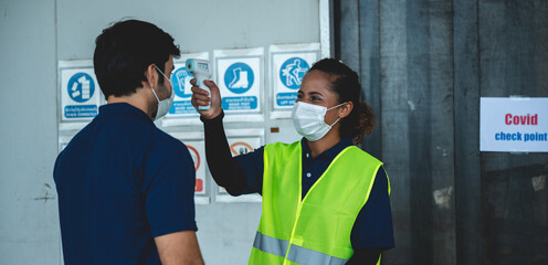 supervisor measuring temperature of workers with thermometer at warehouse factory, construction site, corona virus safety measures checking fever for workers, engineers and foreman