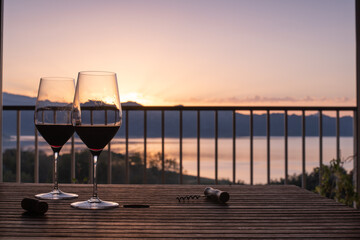 Two red wine glasses for a sunset aperitif on the balcony at home