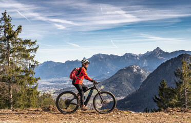 Obraz na płótnie Canvas pretty senior woman riding her electric mountain bike in the mountains of East Allgaeu on warm autumn day with Mount Zugspitze in background
