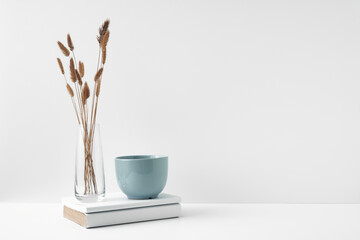 A mug, stack of books and a transparent vase. Eco-friendly materials in interior decor, minimalism....