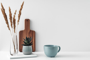 A mug and potted houseplant, a stack of books, a transparent vase and a wooden board. Eco-friendly materials in interior decor, minimalism. Copy space, mock up.