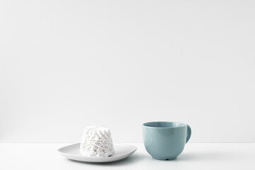 Mug and meringue cake on a white background. Eco-friendly and natural materials in decor and interior design, dessert. Copy space, mock up