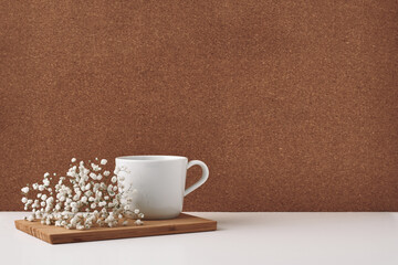 Obraz na płótnie Canvas White cup and flowers on a chalkboard, cork background. Mock up, copy space