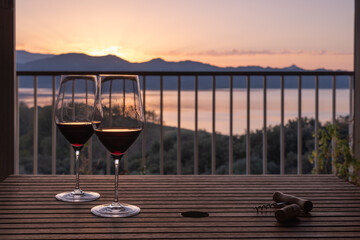 Two red wine glasses for a sunset aperitif on the balcony at home