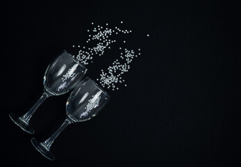Wine glasses with silver confetti on a black background.