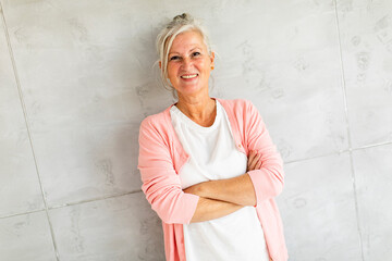 Portrait of beautiful older woman smiling and standing by wall
