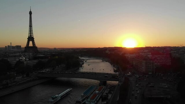 Aerial drone view of Eiffel tower at sunset with orange sun and bridge in Paris, France