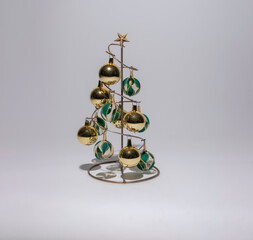 Fototapeta na wymiar árbol navideño metálico con esferas verdes y doradas aislado en fondo blanco