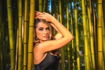 Fototapeta na wymiar Lifestyle, blonde Caucasian girl in a black strappy dress, in a beautiful bamboo in the park outdoors, girl relaxed and enjoying the peace of being outdoors