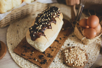 Delicious bread with chocolate spread and sprinkled with nuts on top of it on a wooden board
