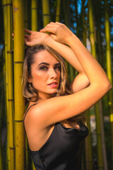 Fototapeta na wymiar Lifestyle, blond Caucasian girl in a black strappy dress, in a beautiful bamboo in the park outdoors, relaxed girl in the photo session