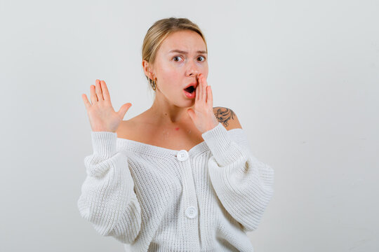  Blonde Lady In Cardigan Showing No Gesture, Keeping Hand Near Mouth And Looking Shocked , Front View.