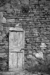 An old wooden door in a disused building in the historic medieval village of Crevole near Murlo in Siena Province, Tuscany, Italy
