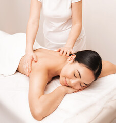 Fototapeta na wymiar Thai massage. Asian woman with closed eyes in pleasure during massage in spa salon