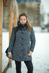 Obraz premium Portrait of a young beautiful girl in the winter in a park in cloudy weather.