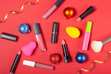 Obraz premium A set of cosmetics, lipstick and lip glosses, brush, mascara on a bright red background. The concept of buying cosmetics, online store, holiday