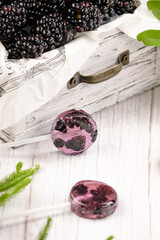 Homemade lollipops made from natural dehydrated bilberry and blackberries on a white wooden background. Healthy vegan vegetarian food with no sweets.