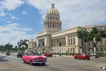Classic cars drive past the Capitolio building, Havana, Cuba
