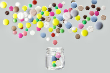 Multicolored medical pills fly out of glass jar