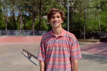 Closeup to the camera amazing man large beautiful smile in a modern skate park holding feeling happy she have hipster outfit