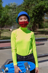 Outside in a urban skate park stylish lady asian looking with a creative protective mask in front...