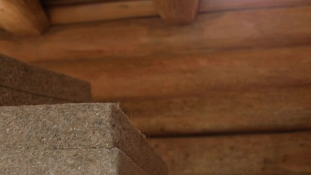 Close up of men's hands lifting a pair of thick hemp wool sheets from a pile, in the building site of an eco friendly house in construction.