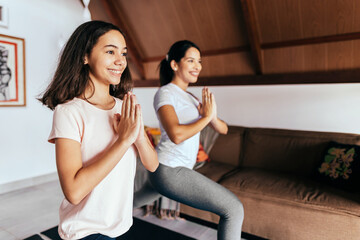 Young woman and child daughter training and stretching at home.