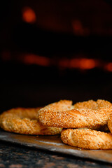 Freshly baked simit baked goods with sesame seeds close-up (Turkish bagel - Gevrek or Kuluri) in front of the hearth. Traditional white bread with sesame seeds for breakfast, close up