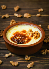 Baked rice pudding - turkish milk dessert sutlac in earthenware casserole with walnuts. Turkish Cuisine dessert varieties. Close up