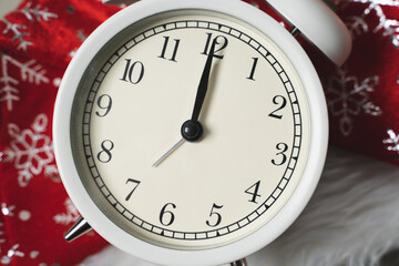 White alarm clock lying on the background of a red christmas hat