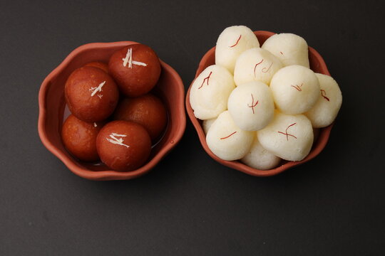 Famous Indian desserts rasgulla/ rosogulla/ roshogulla and gulab jamun/ gulabjam served in earthen bowl.
