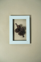 Volumetric painting on a light green background with a blue frame and pine cones