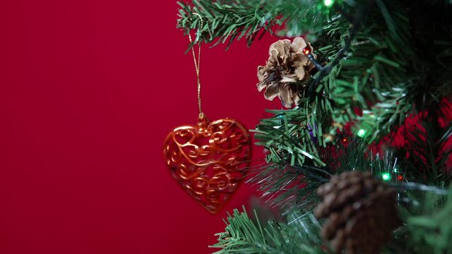 Heart of a Christmas toy hung on a Christmas tree on a red background close-up