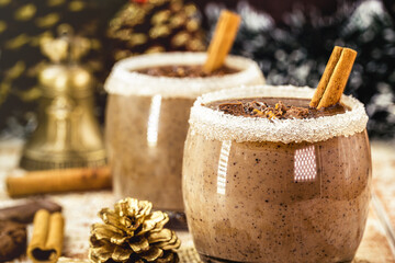 cups with hot chocolate, cinnamon, sugar and milk, with steam smoke, hot christmas drink