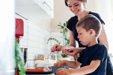 Mom and young son cook sweet cakes in the kitchen