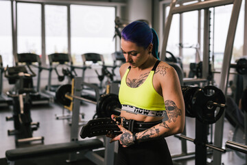 tattooed woman preparing for power lifting in gym