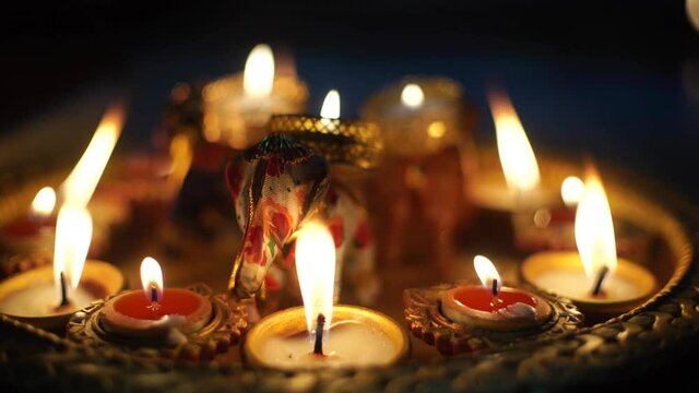 Low shot of diya oil lamps with wicks lit with flames and hand painted decorated beautifully with a handmade cloth elephant ornament in the middle