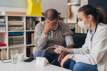 woman doctor visiting senior man at his home, coronavirus concept