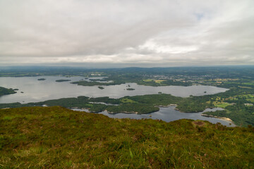 Panoramic view of the Irish countryside with trees, green vegetation and lakes with mountains and hills, cloudy day in Ireland