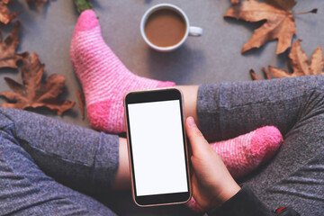 A woman in warm knitted socks is holding a telephone in her hands, next is a coffee cup. Autumn...