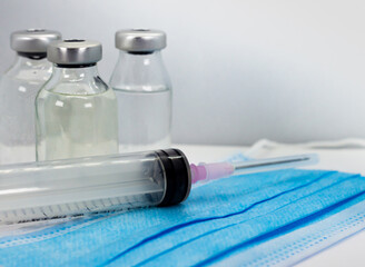 Vaccine Vial, Syringe and blue Medical Face Mask