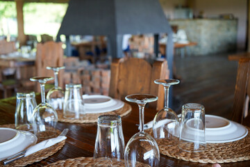 the wooden table is set with wine and drink glasses, Cutlery and porcelain plates on beautiful wicker napkins