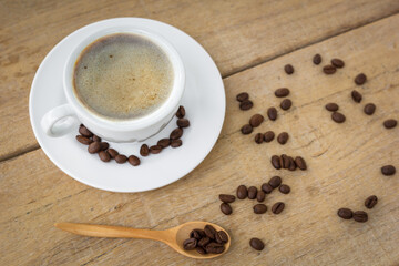 hot coffee and bubble in white coffee cup and saucer with wood spoon on black background.