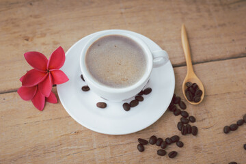 hot latte coffee and bubble in white coffee cup and saucer with a spoon on wooden background.