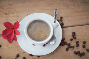 hot coffee and bubble in white coffee cup and saucer with a spoon on wooden background.
