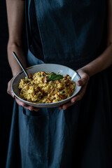 Risotto with chanterelles and saga leaves. Woman holding plate with risotto
