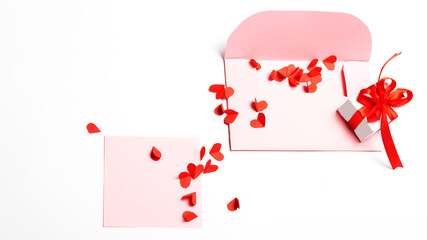 Valentine's Day. Open pink an envelopes with small cut paper heart and gift box with red bow and and blank sheet. Writing a love letter. Message.Top view.Valentine concept. copy space. 