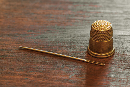 A Sewing Needle And An Antique Gold Thimble.