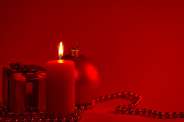 Burning candle and Christmas decoration red dark background, elegant low-key shot with festive mood