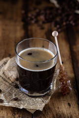 Black coffee in a glass with brown sugar crystals